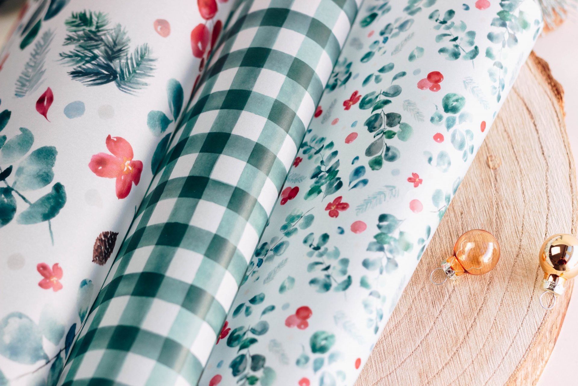 Rolos de papel de embrulho com padrões florais e xadrez sobre base de madeira