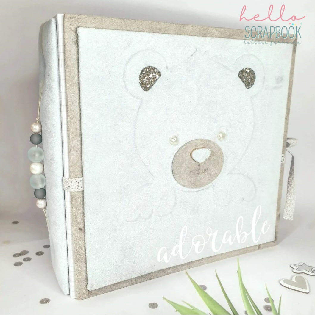Álbum de scrapbook com capa branca e bege, urso desenhado com detalhes brilhantes, palavra 'adorable' e texto 'hello SCRAPBOOK'