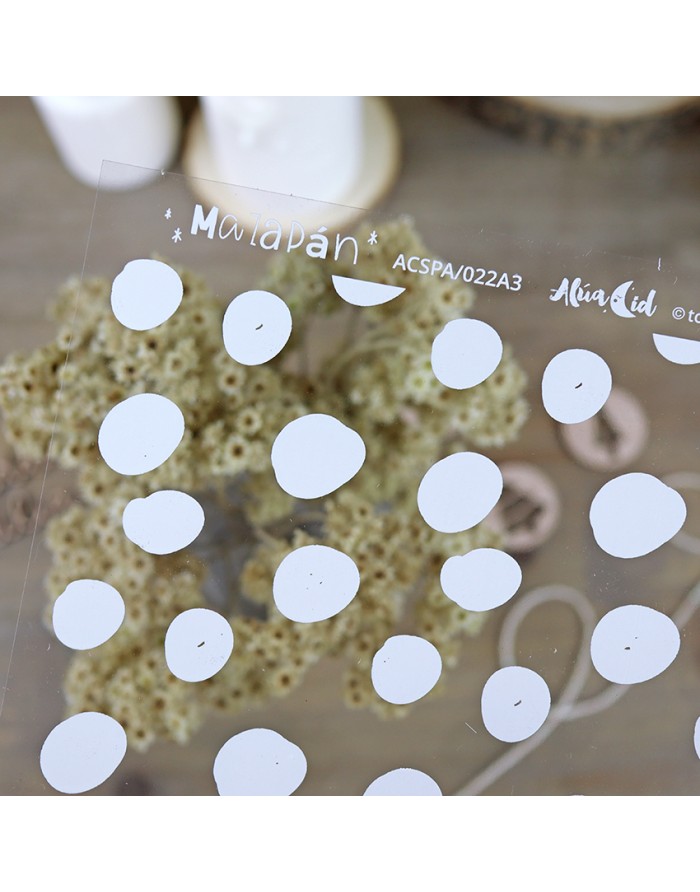 Placa transparente com bolinhas brancas e texto, sobre superfície de madeira com fundo desfocado