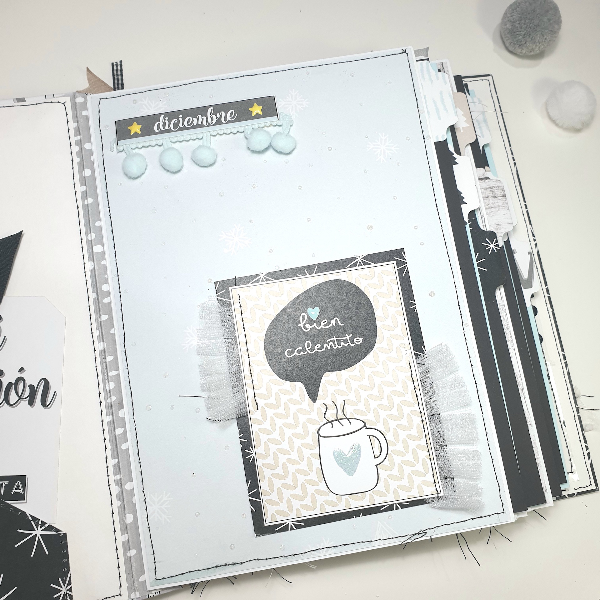 Página de scrapbook decorada com papel azul e etiquetas 'diciembre' e 'bien calentito' com ilustração de caneca quente