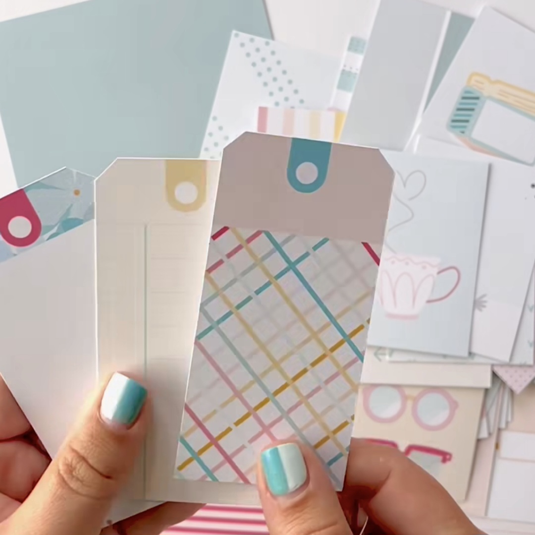 Mãos segurando cartões decorativos com padrões coloridos e abas arredondadas.