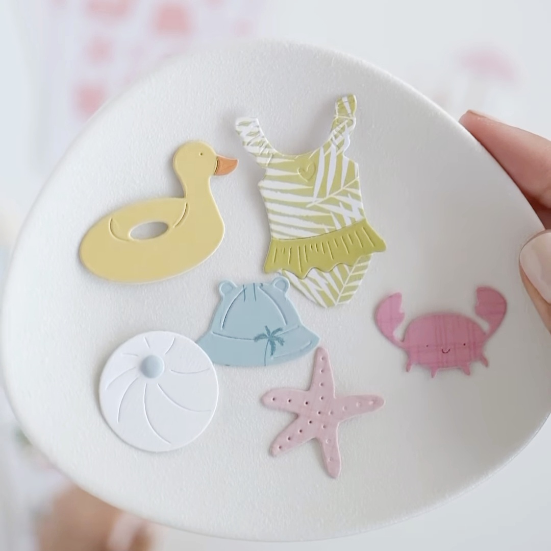 Ímanes decorativos coloridos em forma de animais e objetos de praia num prato branco