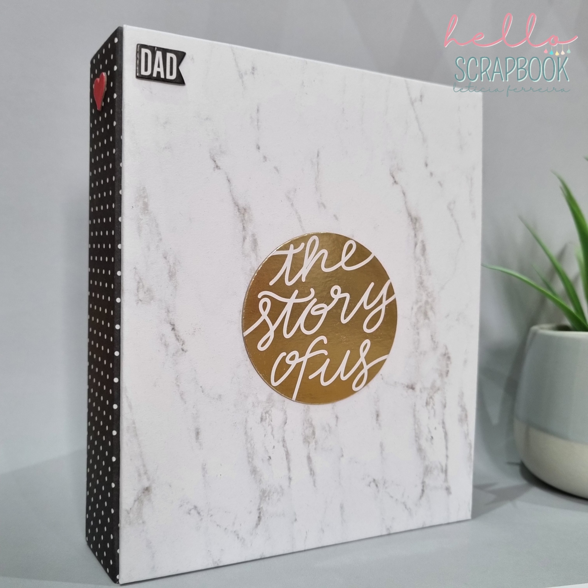 Caixa ou álbum branco com padrão mármore, texto 'the story of us' e etiqueta 'DAD'