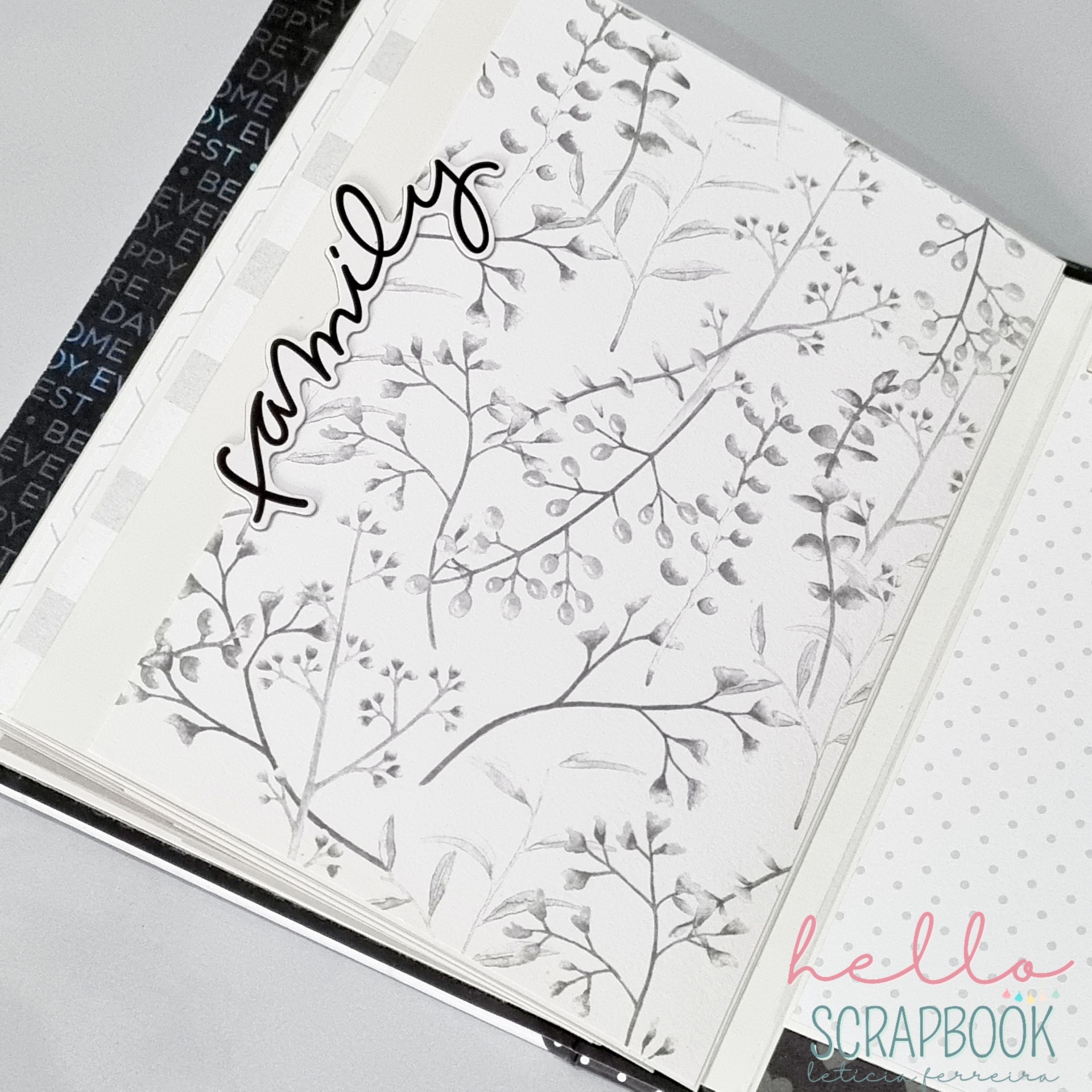 Livro de scrapbook aberto com decoração floral cinzenta e texto 'family'