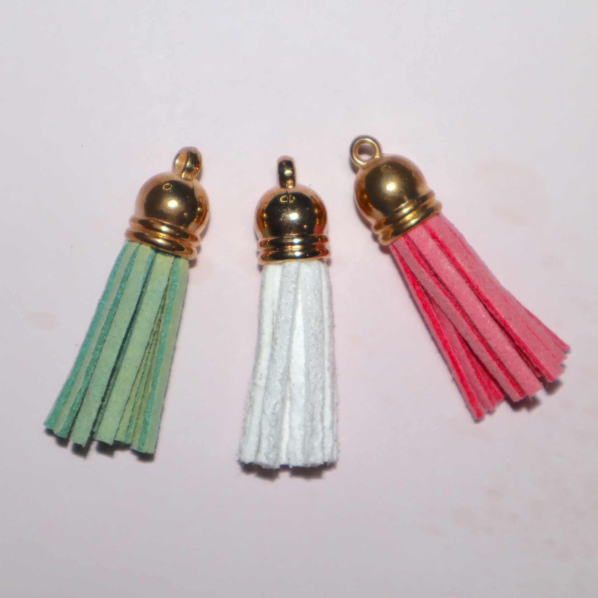 Três pendentes tassel em camurça verde, branco e vermelho com acabamento dourado