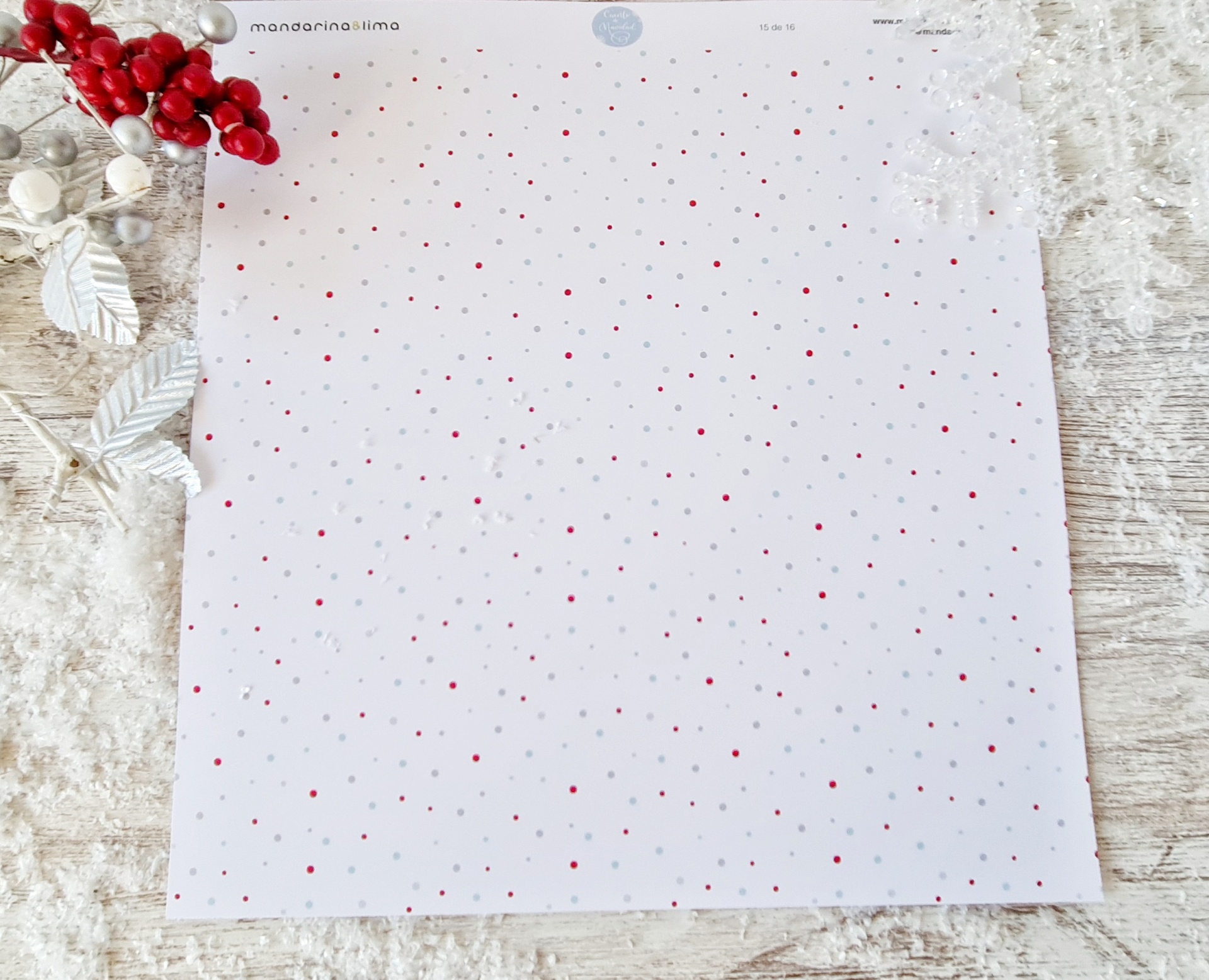 Papel branco com pontos vermelhos e cinzentos em superfície rústica com decoração natalícia