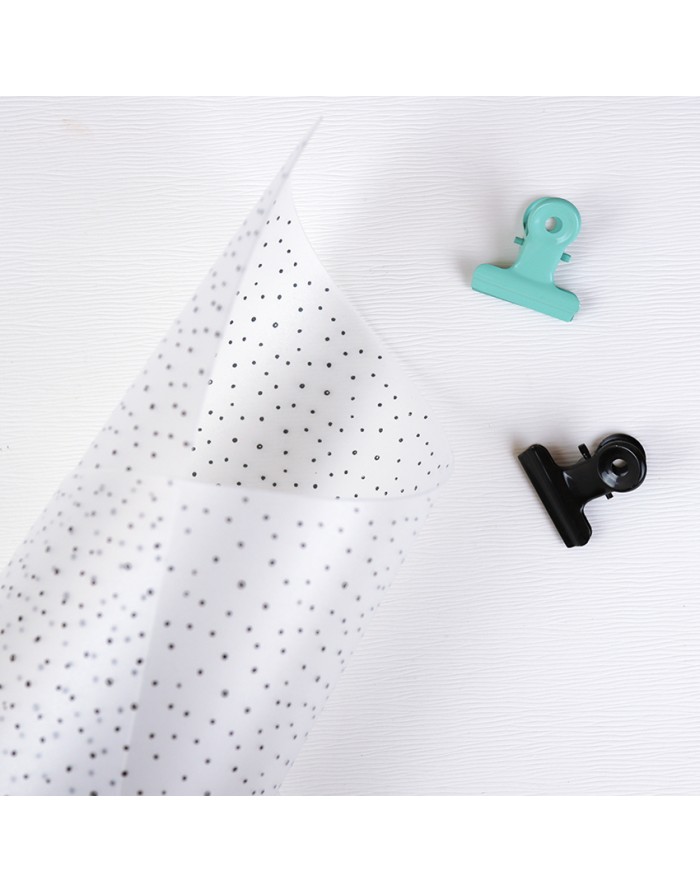 Papel transparente com estrelas pretas e dois clipes coloridos sobre fundo branco