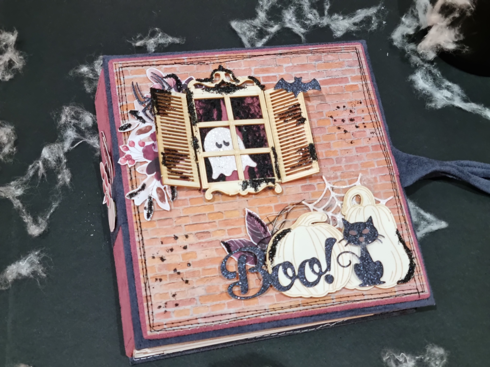 Caixa decorativa com janela de venezianas e decorações de Halloween sobre fundo de tijolos