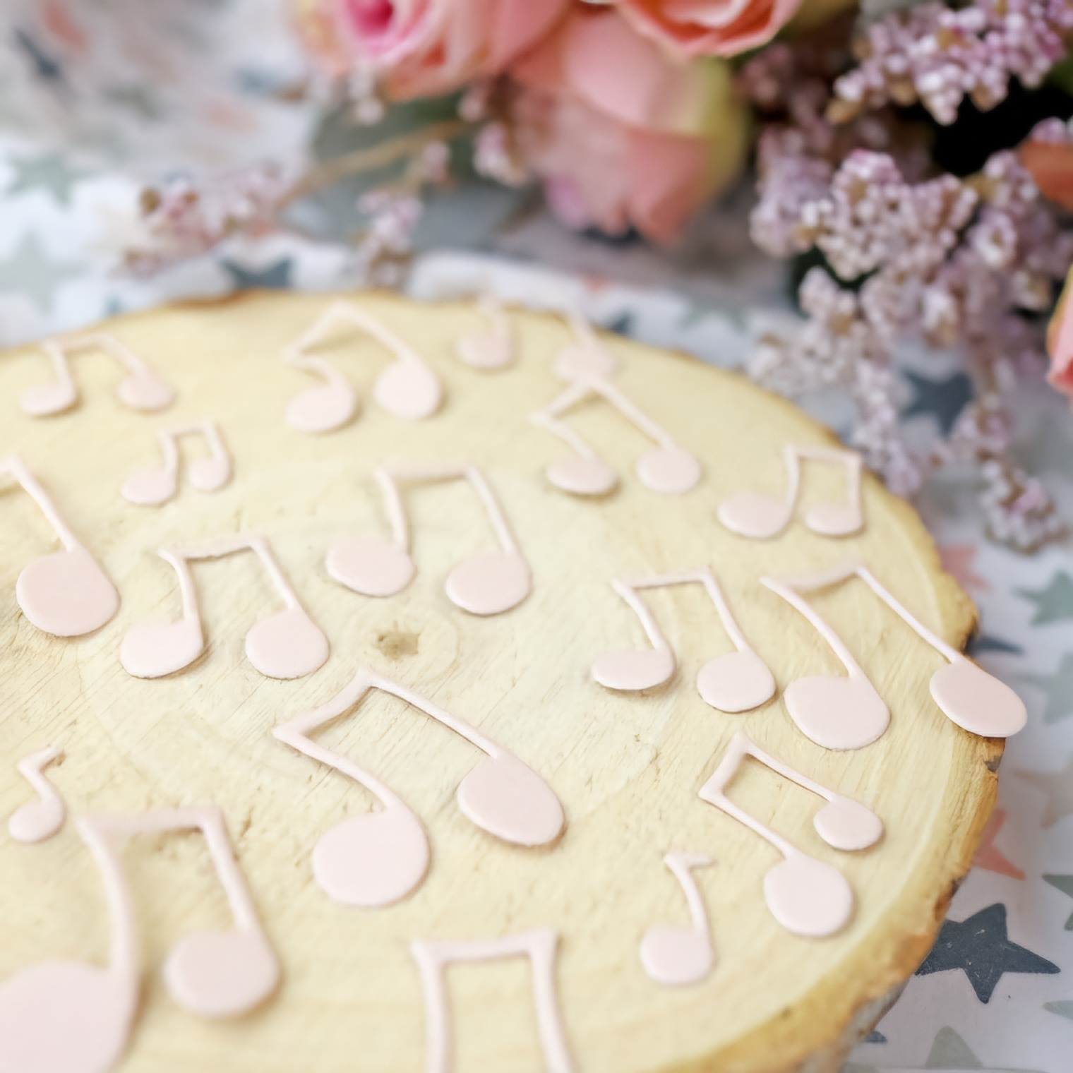 Placa de madeira com notas musicais cor-de-rosa e flores ao fundo