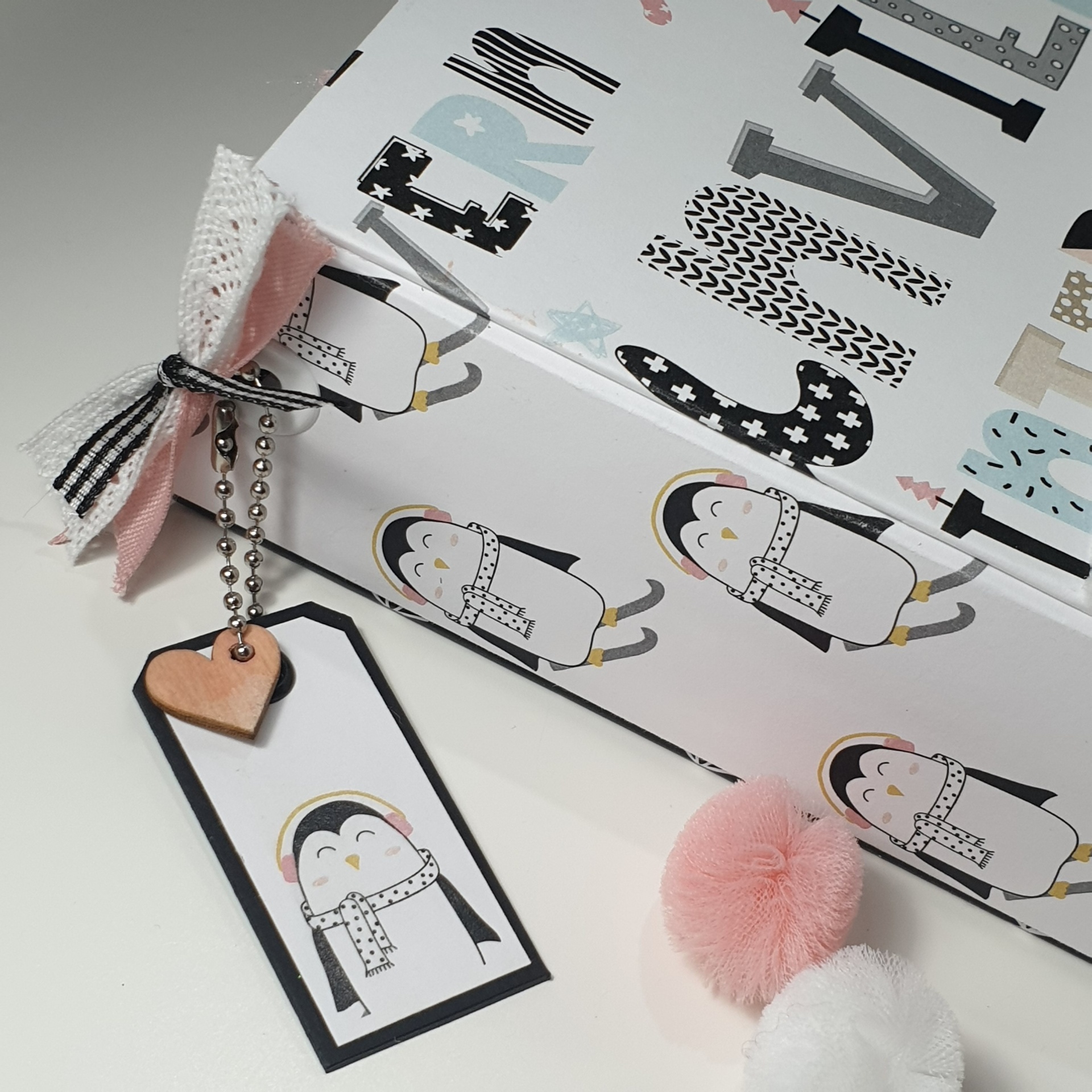 Caixa decorativa com padrão de pinguins e etiqueta com pinguim e laço de tecido