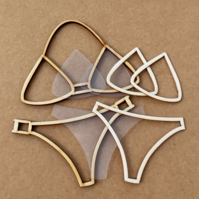 Partes de biquíni em madeira clara e tecido transparente sobre fundo castanho