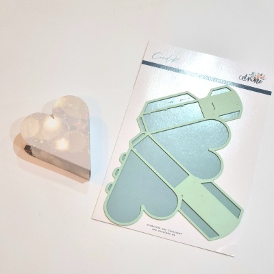 Caixa em forma de coração prateada e molde em cartão verde claro sobre fundo branco