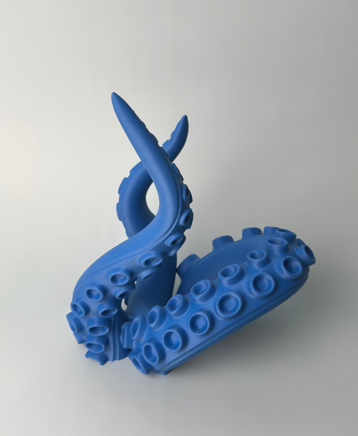 Escultura azul de tentáculos de polvo decorativos em fundo branco.