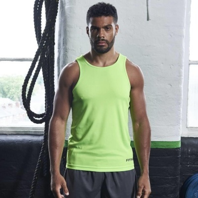 Homem com regata desportiva verde-limão e calças cinzentas em ginásio com cordas penduradas