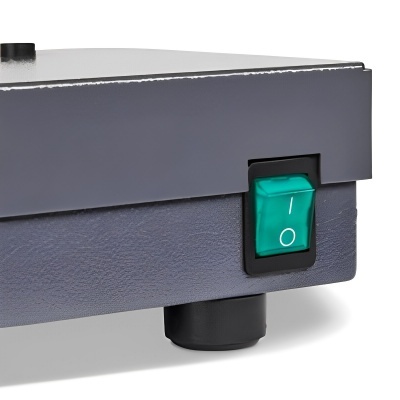 Close-up de interruptor verde em aparelho eletrônico cinza escuro com base texturizada.