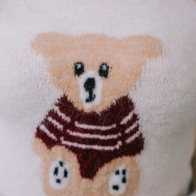 Camisola branca com urso castanho de malha e camisola às riscas vermelhas e brancas