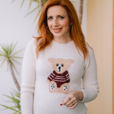 mulher com camisola branca com urso e saia vinho, plantas ao fundo