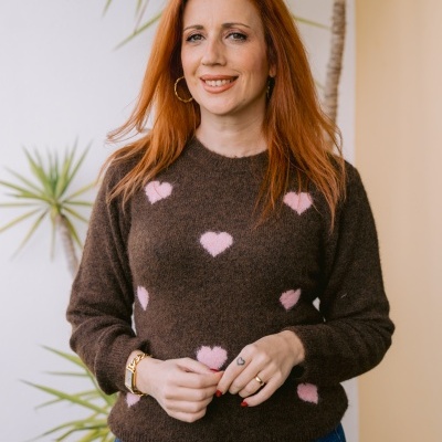 Mulher com camisola castanha com corações rosas e jeans azuis