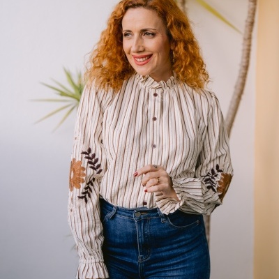 Blusa feminina riscada com bordados florais e jeans azul escuro.