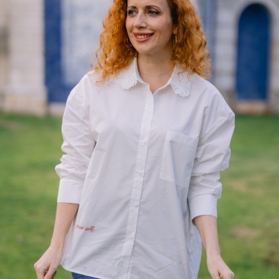 Mulher com camisa branca de algodão e calças de ganga azuis num jardim