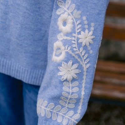 Manga de camisola azul com bordados florais brancos