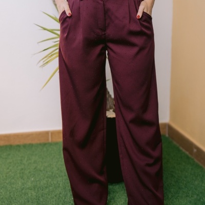 Calças bordô largas com pontos pretos usadas com camisa branca e sapatos dourados