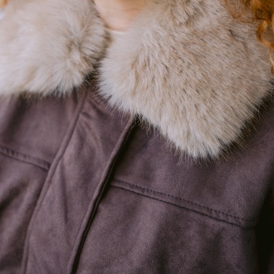 Casaco castanho com gola de pelo creme e brinco dourado em espiral