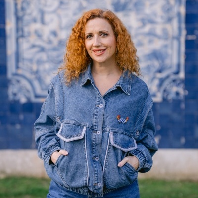 Casaco de ganga azul com bolsos e bordado de galinha usado por mulher.