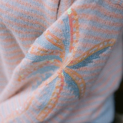 Camisola de malha riscada com padrão de estrela em lantejoulas no cotovelo.