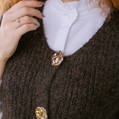 Casaco castanho felpudo com botões dourados e camisa branca com gola franzida