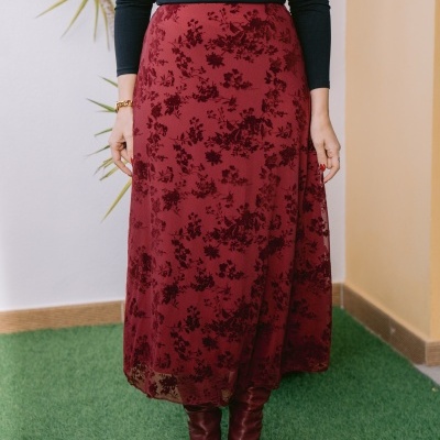 Saia midi vermelha com padrão floral, botas vermelhas e blusa preta com detalhes em renda