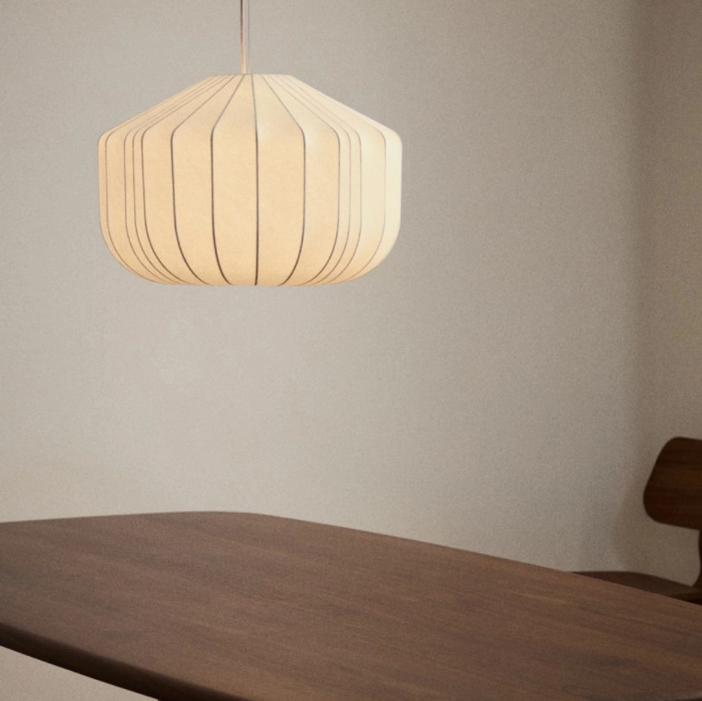 Candeeiro de teto em tecido seda branco Somaran Ø51 Candeeiro de teto creme suspenso, mesa de madeira castanha e cadeira parcialmente visível.