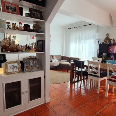 Sala de jantar e estar com mesa branca e estantes com livros e decoração