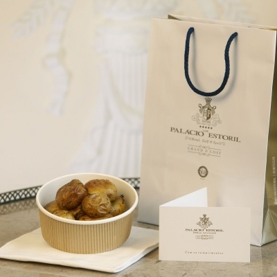 Sacola de papel bege do Palácio Estoril com bolinhos num recipiente e cartão de visita