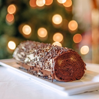 Rolo de chocolate coberto com granulados de chocolate num prato branco