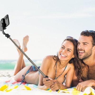 Casal na praia a tirar selfie com selfie stick e telemóvel