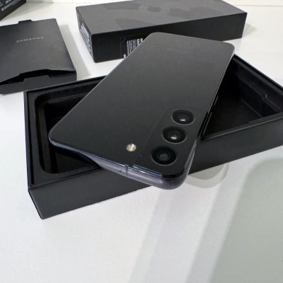 Smartphone preto com três câmaras traseiras e embalagem preta aberta