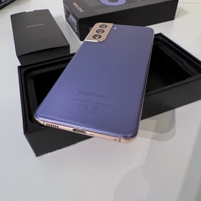 Smartphone Samsung lilás com moldura dourada e caixa preta aberta.