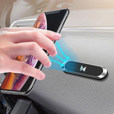 Suporte magnético preto para telemóvel no tabuleiro do carro com mão segurando smartphone.