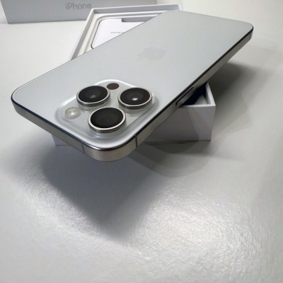 Smartphone iPhone prateado com três câmaras traseiras sobre caixa branca com texto iPhone