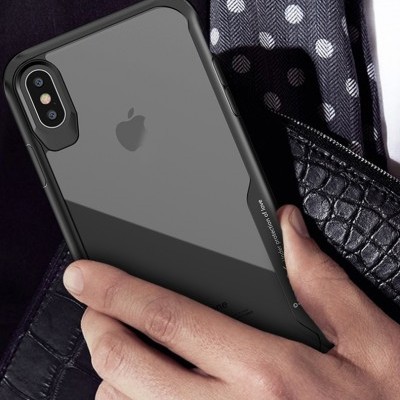 Capa transparente para iPhone com bordas pretas numa mão sobre fundo com tecido azul de bolinhas e pele preta texturizada