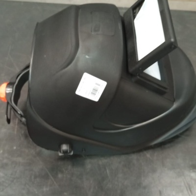 Máscara de soldador preta com visor rectangular sobre mesa metálica