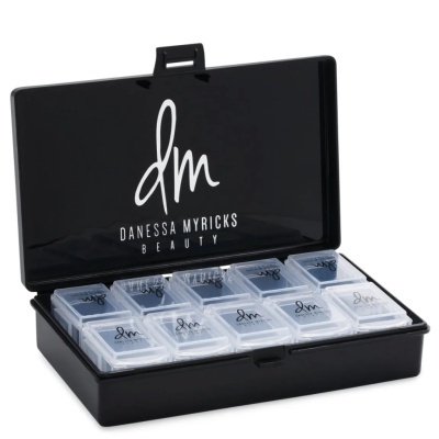 Estojo preto aberto com 10 recipientes transparentes pequenos organizados dentro, com o logótipo 'dm Danessa Myricks Beauty'