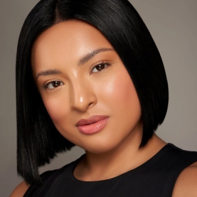 Mulher com cabelo curto preto e pele morena com fundo cinza