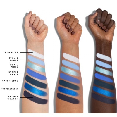 amostras de sombras de olhos em vários tons de azul e preto em três braços de diferentes tons de pele