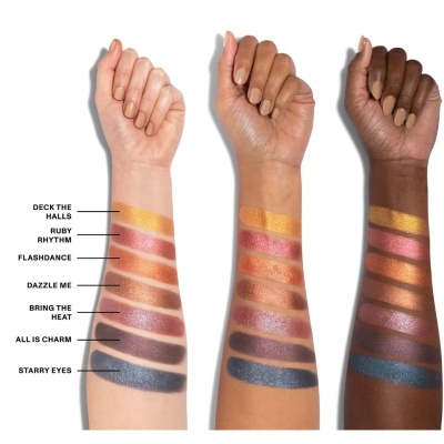 Três braços com diferentes tons de pele mostrando sombras de olhos coloridas e metálicas em amostras largas alinhadas verticalmente.