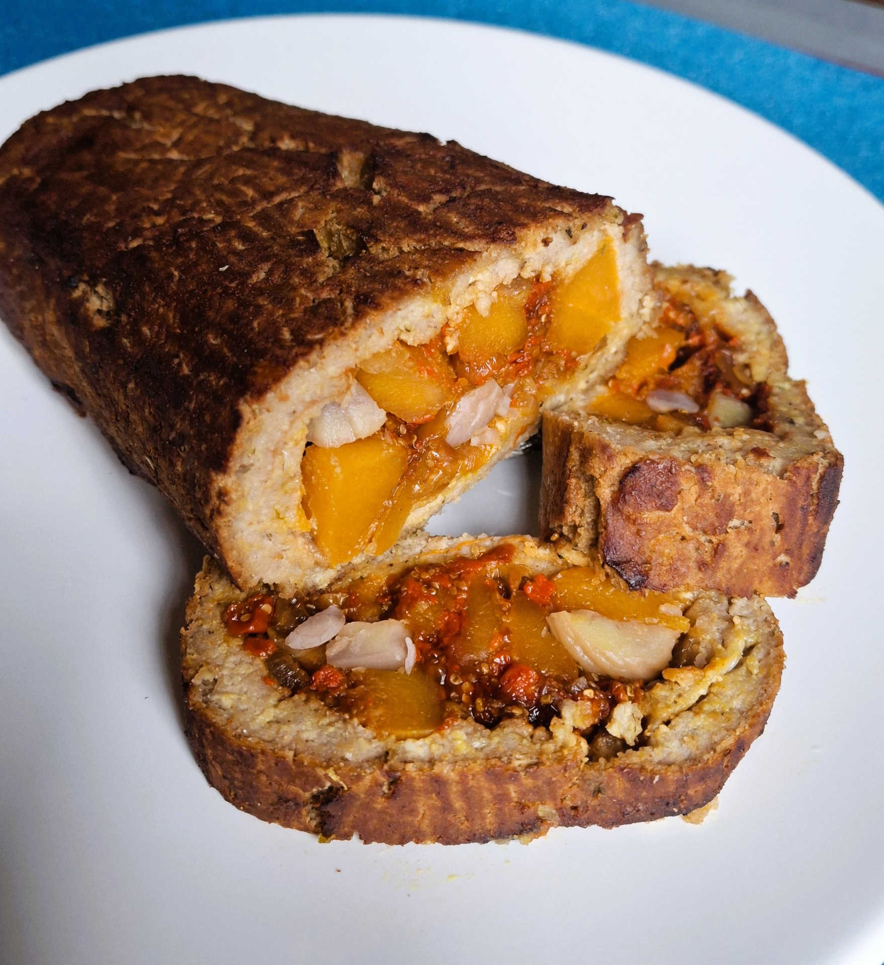 Assado vegetal sem seitan Pão ou bolo recheado com pedaços laranja e branco servido em prato branco