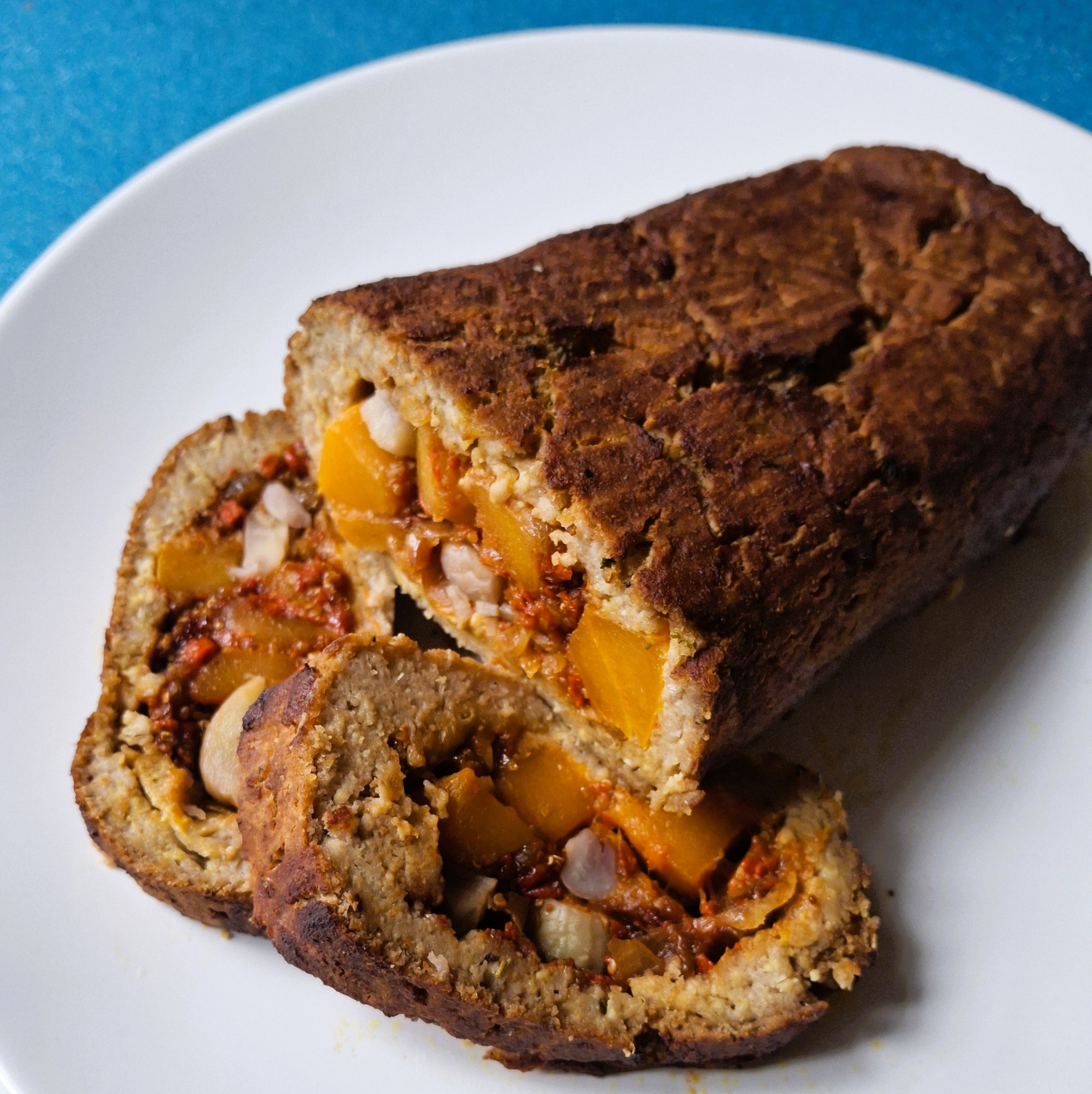 Assado vegetal sem seitan Almondega vegetal recheada e fatiada num prato branco