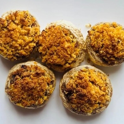 Cinco cogumelos recheados com crosta dourada sobre fundo branco