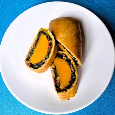 Massa assada cortada ao meio mostrando recheio laranja e escuro em prato branco